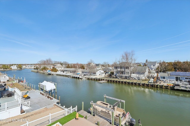 dock area featuring a residential view, a water view, boat lift, and fence