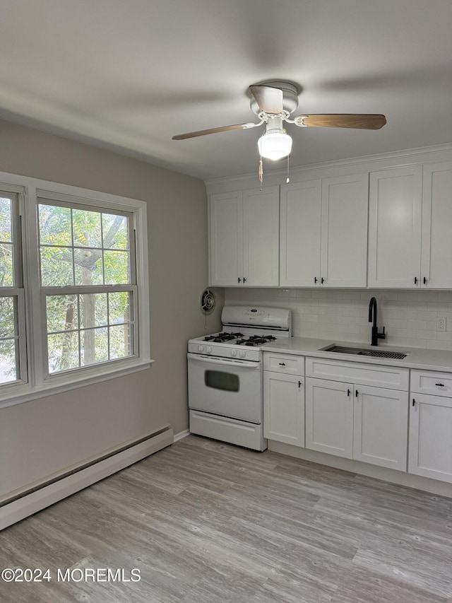 kitchen featuring a sink, white cabinets, baseboard heating, decorative backsplash, and gas range gas stove