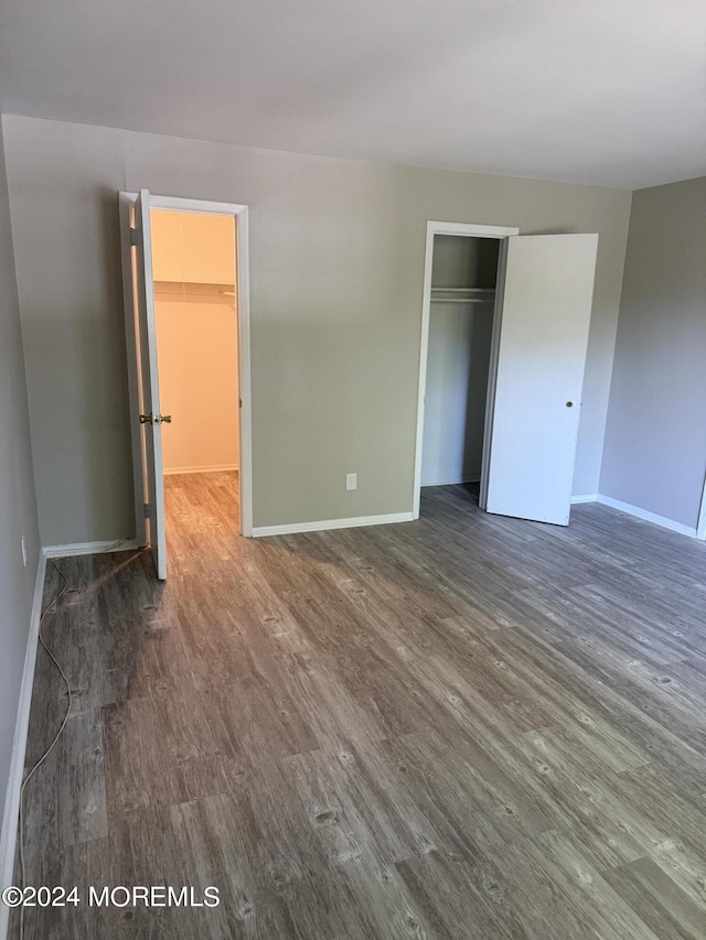 unfurnished bedroom with a closet, dark wood finished floors, and baseboards