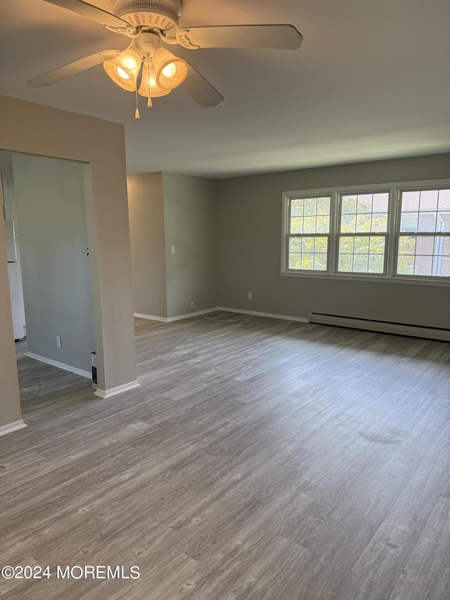 unfurnished room with a baseboard radiator, a healthy amount of sunlight, and wood finished floors