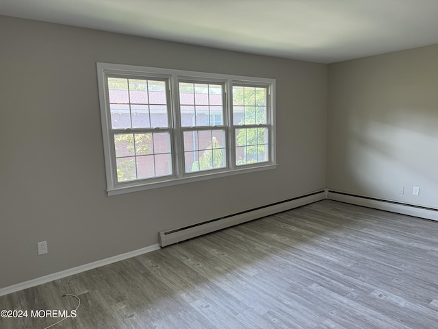 spare room featuring baseboards, wood finished floors, and a healthy amount of sunlight