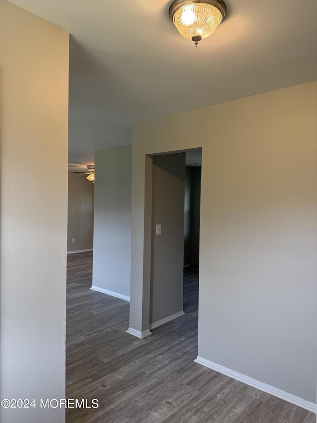 empty room with ceiling fan, dark wood-type flooring, and baseboards