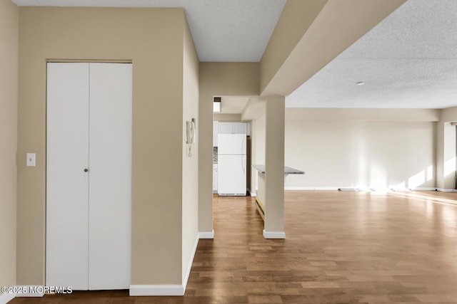 hall featuring wood finished floors, baseboards, and a textured ceiling