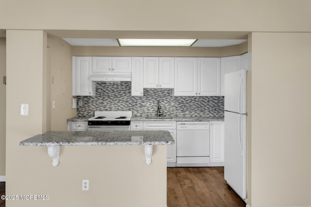 kitchen featuring under cabinet range hood, white cabinetry, white appliances, and a breakfast bar area