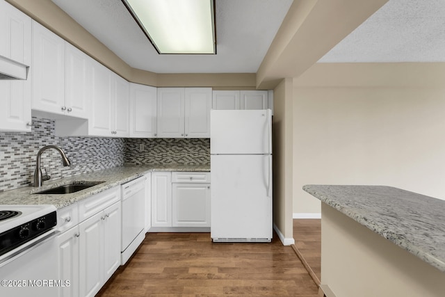 kitchen featuring a sink, light stone counters, wood finished floors, white appliances, and white cabinets