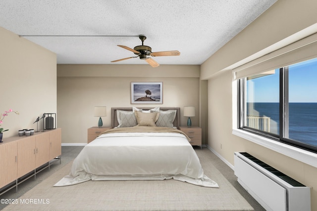 bedroom featuring baseboards, light colored carpet, radiator heating unit, and a textured ceiling