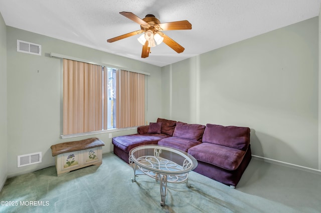 carpeted living room featuring a ceiling fan, visible vents, and a textured ceiling