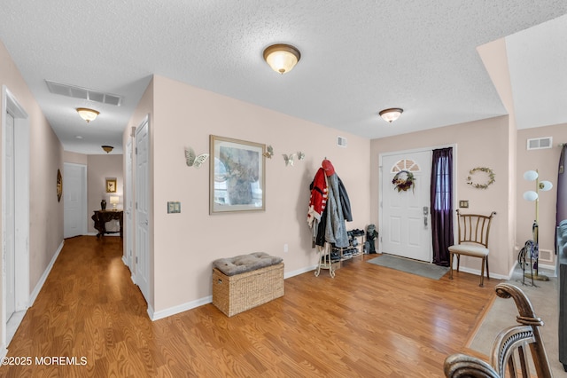 foyer entrance featuring light wood-style floors, visible vents, and a textured ceiling