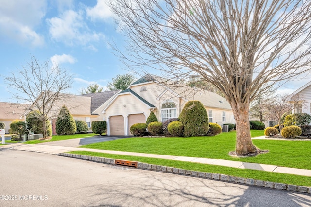 view of front of property featuring an attached garage, a front lawn, and aphalt driveway