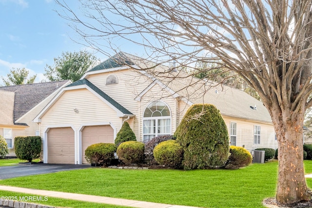 view of front of home featuring central air condition unit, a garage, a shingled roof, driveway, and a front lawn