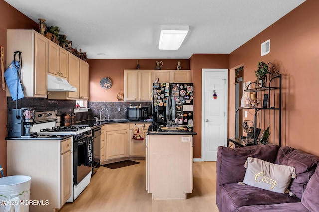 kitchen with visible vents, dark countertops, open floor plan, under cabinet range hood, and black appliances