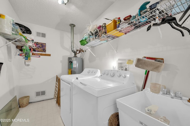 washroom featuring laundry area, water heater, visible vents, and a sink