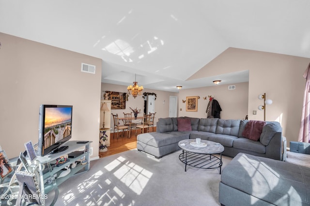 living area featuring a chandelier, visible vents, and vaulted ceiling