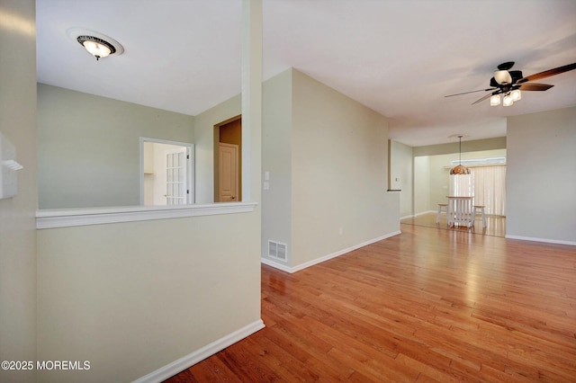 spare room with visible vents, ceiling fan, baseboards, and wood finished floors