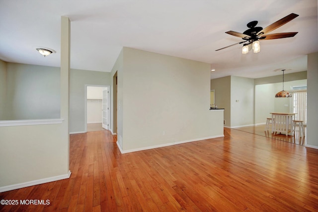 empty room featuring baseboards, a ceiling fan, and light wood-style floors