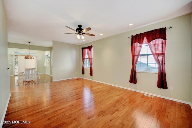 empty room with baseboards, a healthy amount of sunlight, visible vents, and light wood-style floors