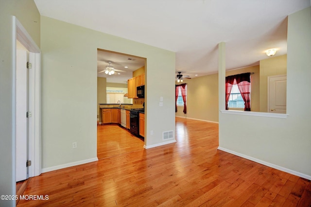 interior space with light wood-type flooring, visible vents, a sink, and baseboards