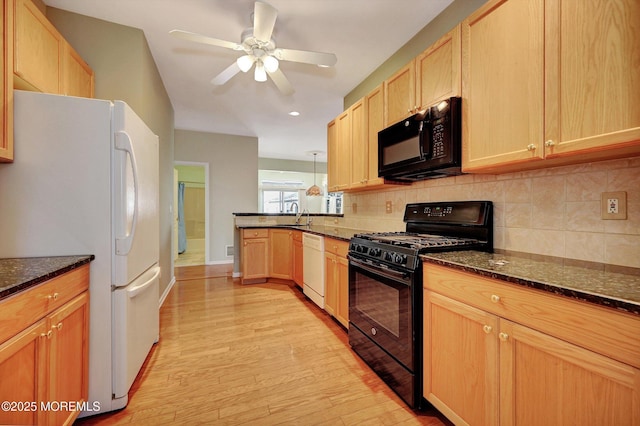 kitchen featuring tasteful backsplash, light wood-style floors, dark stone countertops, a peninsula, and black appliances