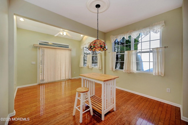 dining space with a ceiling fan, baseboards, and hardwood / wood-style flooring