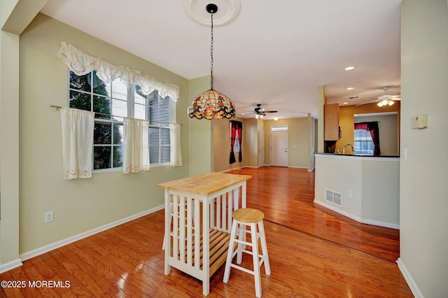 dining space featuring baseboards, a healthy amount of sunlight, visible vents, and light wood-style floors