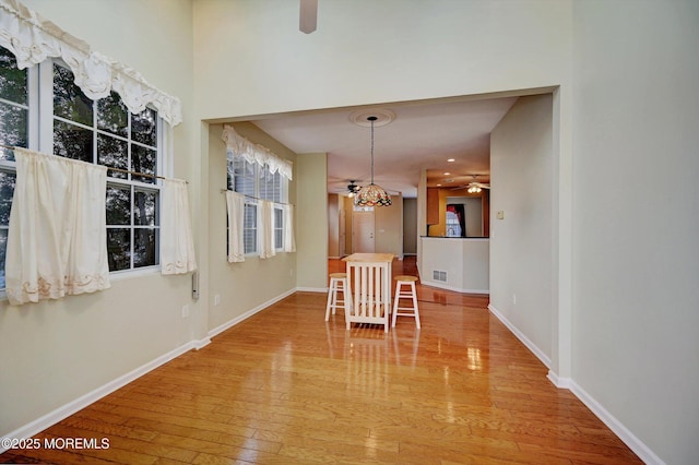 unfurnished dining area with wood-type flooring, visible vents, baseboards, and ceiling fan