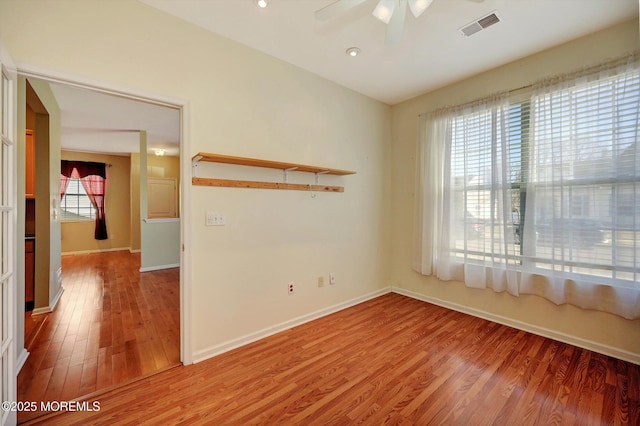 empty room featuring baseboards, light wood-style flooring, visible vents, and a ceiling fan