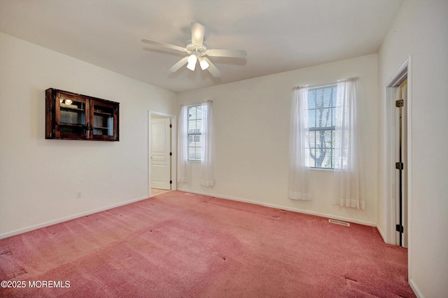 carpeted spare room with ceiling fan, visible vents, and baseboards