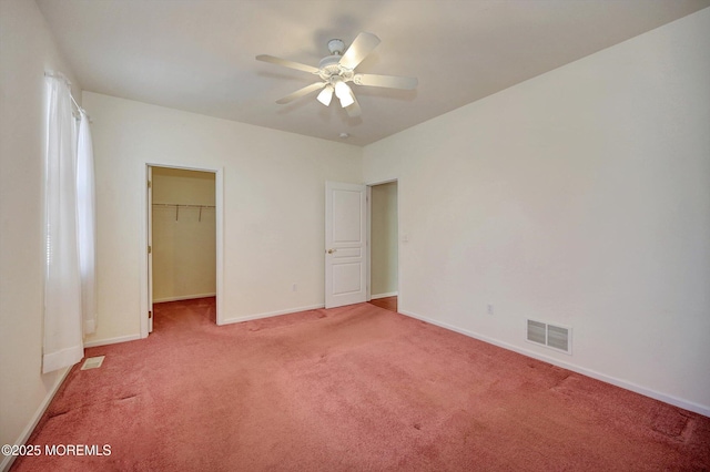 unfurnished bedroom with light carpet, baseboards, visible vents, a ceiling fan, and a spacious closet