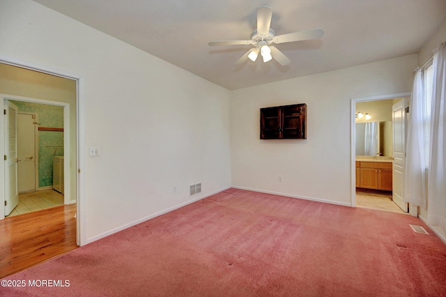 unfurnished bedroom with ensuite bath, visible vents, and light colored carpet