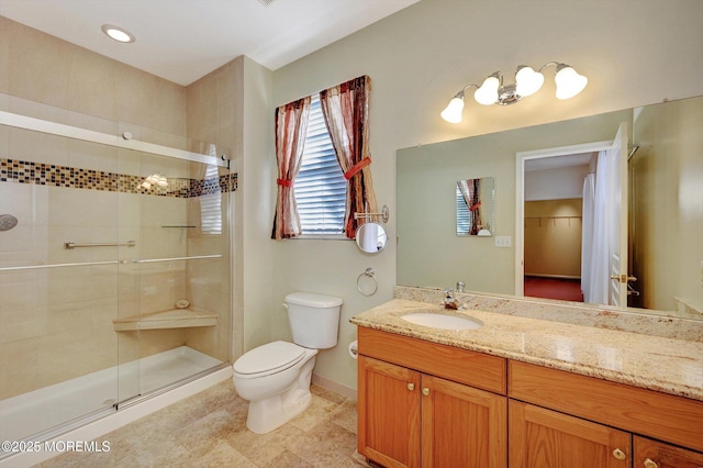 bathroom featuring vanity, a shower stall, toilet, and baseboards