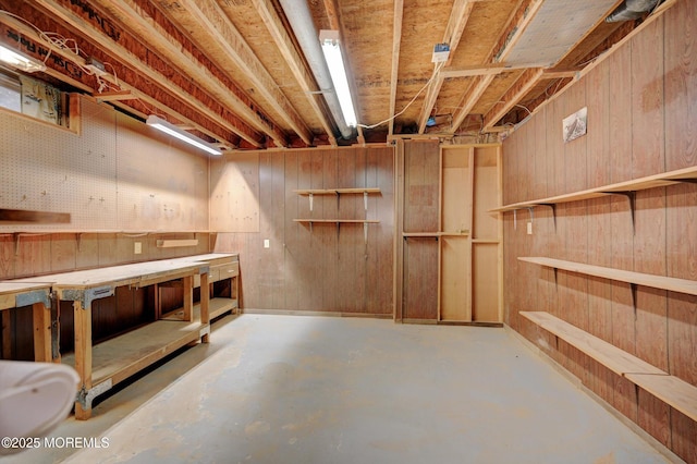 unfinished basement with wood walls and a workshop area