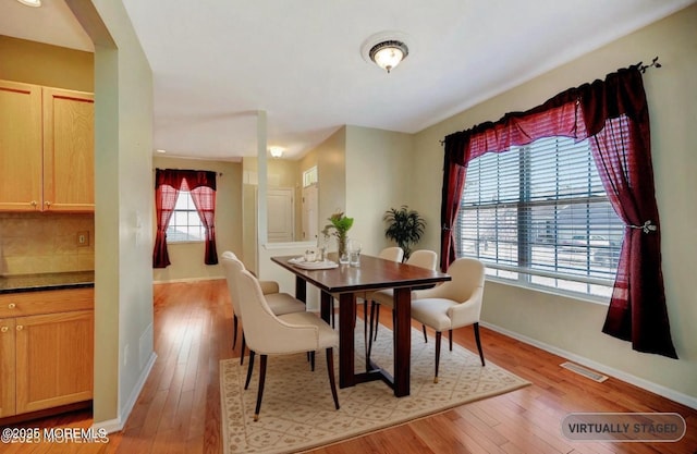 dining area with light wood finished floors, visible vents, and baseboards