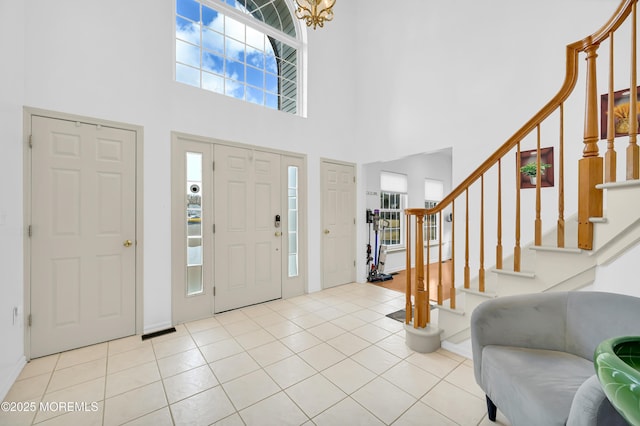 tiled foyer featuring stairs and a towering ceiling