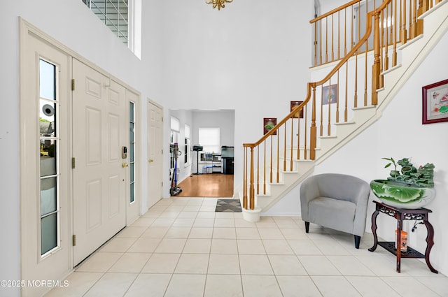 foyer entrance with tile patterned flooring, a towering ceiling, and stairs