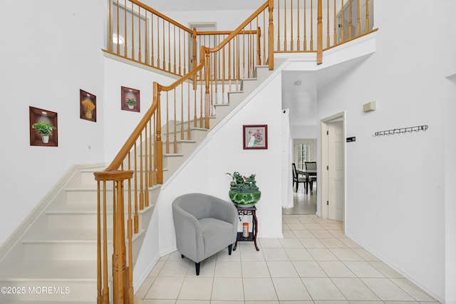 stairs featuring a towering ceiling, tile patterned flooring, and baseboards