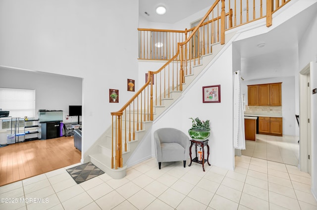 stairs with tile patterned flooring, visible vents, and a high ceiling