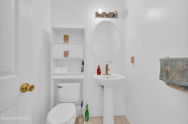 half bathroom with a sink, tile patterned flooring, and toilet