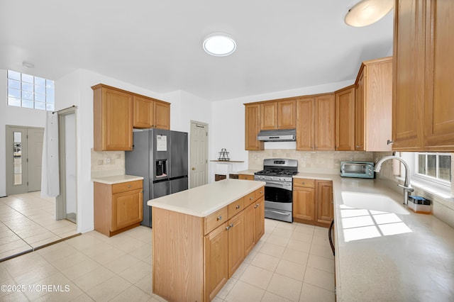 kitchen with a center island, light countertops, under cabinet range hood, refrigerator with ice dispenser, and stainless steel range with gas stovetop