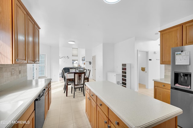 kitchen with a kitchen island, stainless steel fridge with ice dispenser, black dishwasher, light countertops, and decorative backsplash