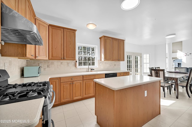 kitchen with extractor fan, a kitchen island, light countertops, french doors, and stainless steel range with gas cooktop