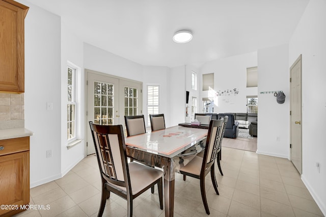 dining space with french doors, baseboards, and light tile patterned floors