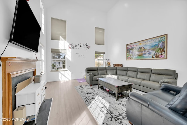 living area with a high ceiling, light wood-type flooring, and a fireplace