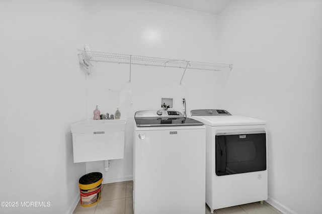 laundry room featuring laundry area, light tile patterned floors, baseboards, and separate washer and dryer