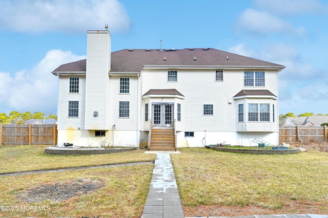 back of house with french doors, fence, a chimney, and a lawn