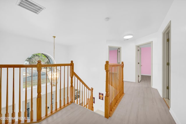 hall featuring visible vents, baseboards, an upstairs landing, and an inviting chandelier