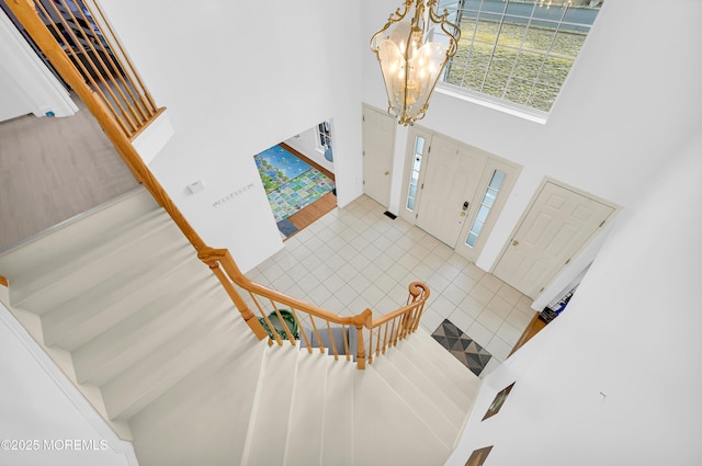 entrance foyer with tile patterned flooring, a high ceiling, stairway, and a chandelier