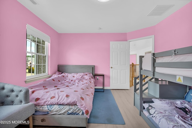 bedroom featuring light wood-style flooring, visible vents, and baseboards