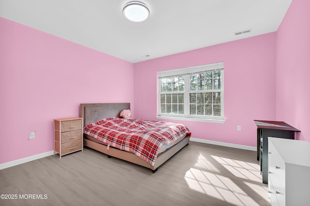 bedroom with wood finished floors, visible vents, and baseboards