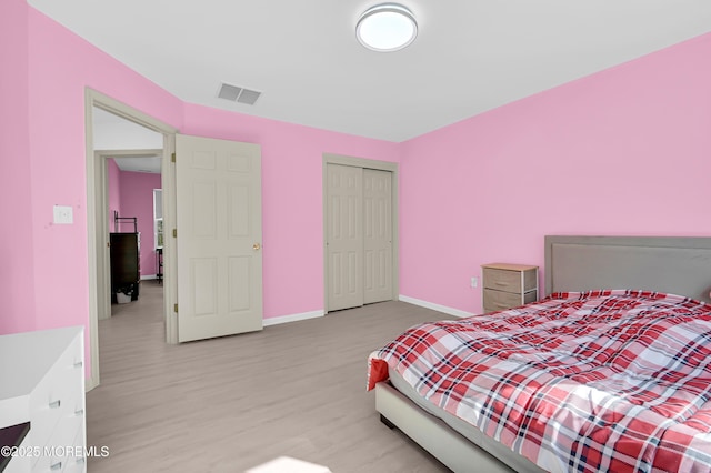 bedroom featuring light wood-style flooring, a closet, visible vents, and baseboards