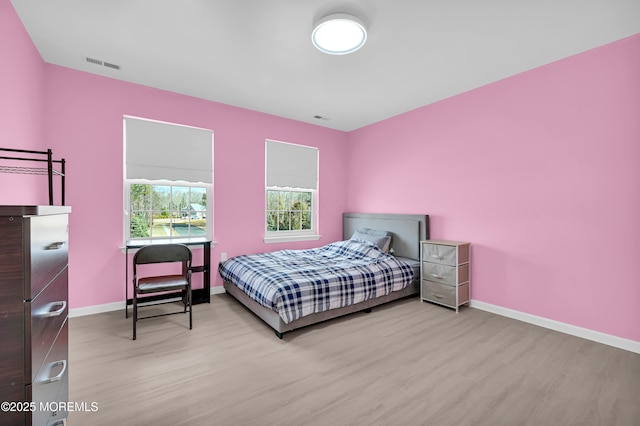 bedroom featuring visible vents, baseboards, and wood finished floors